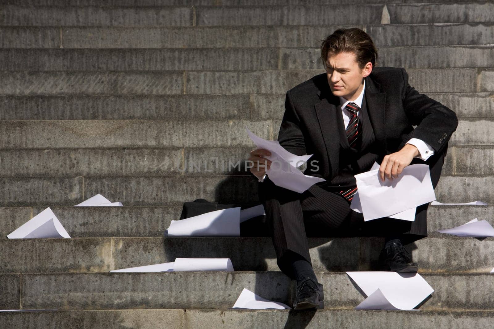 Unhappy businessman suffering from world financial crisis while sitting on stairs