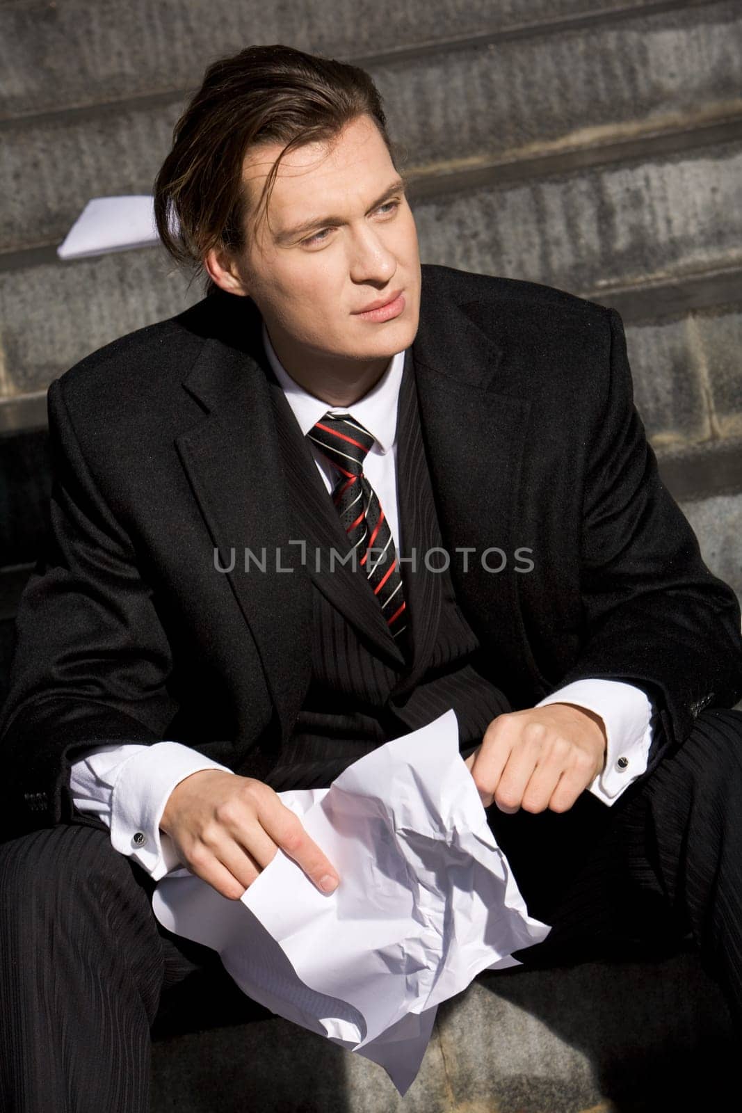 Portrait of handsome business leader with crumpled piece of paper in hands