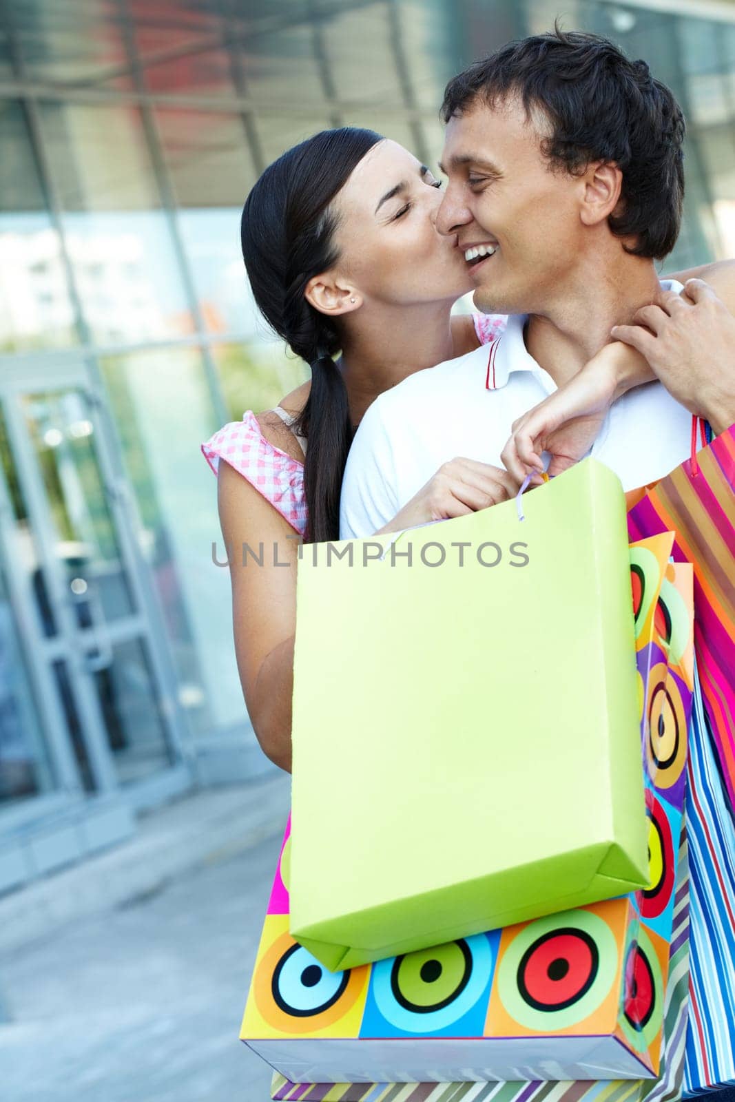 Young girl kissing her boyfriend with shopping bags