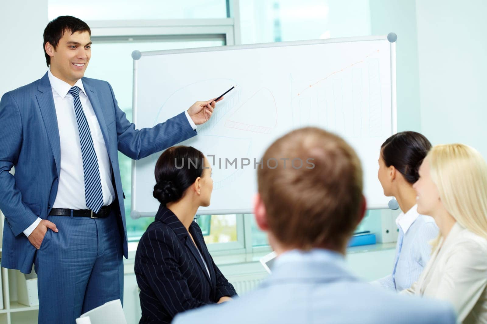 A business man showing something on a whiteboard to his colleagues