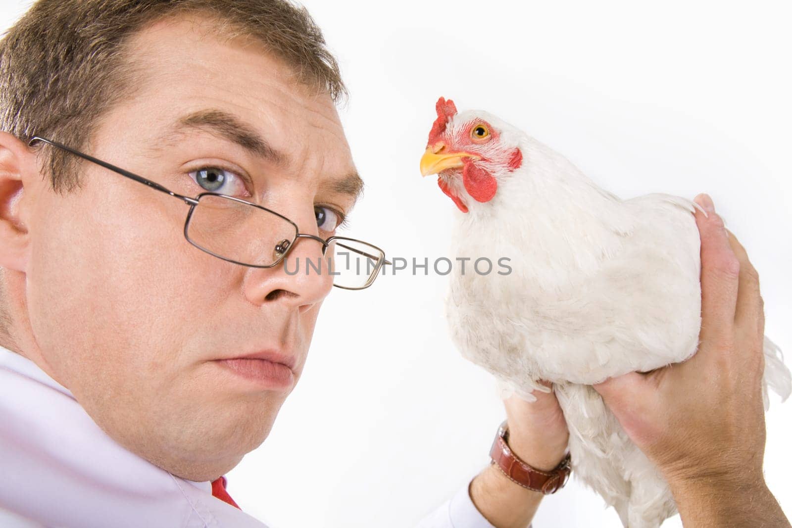 Photo of serious man holding white hen in hands and looking at camera