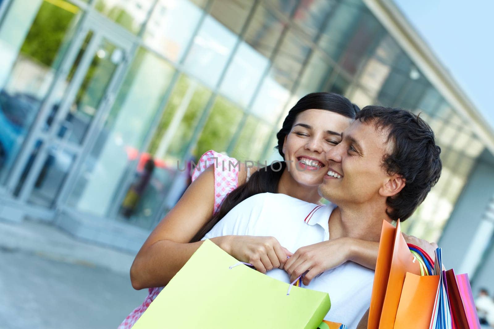 Young girl embracing her boyfriend with shopping bags