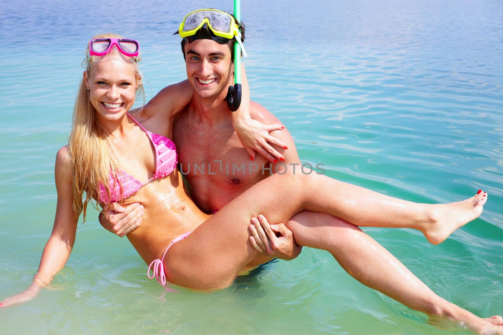 Portrait of happy guy holding his girlfriend while standing in water
