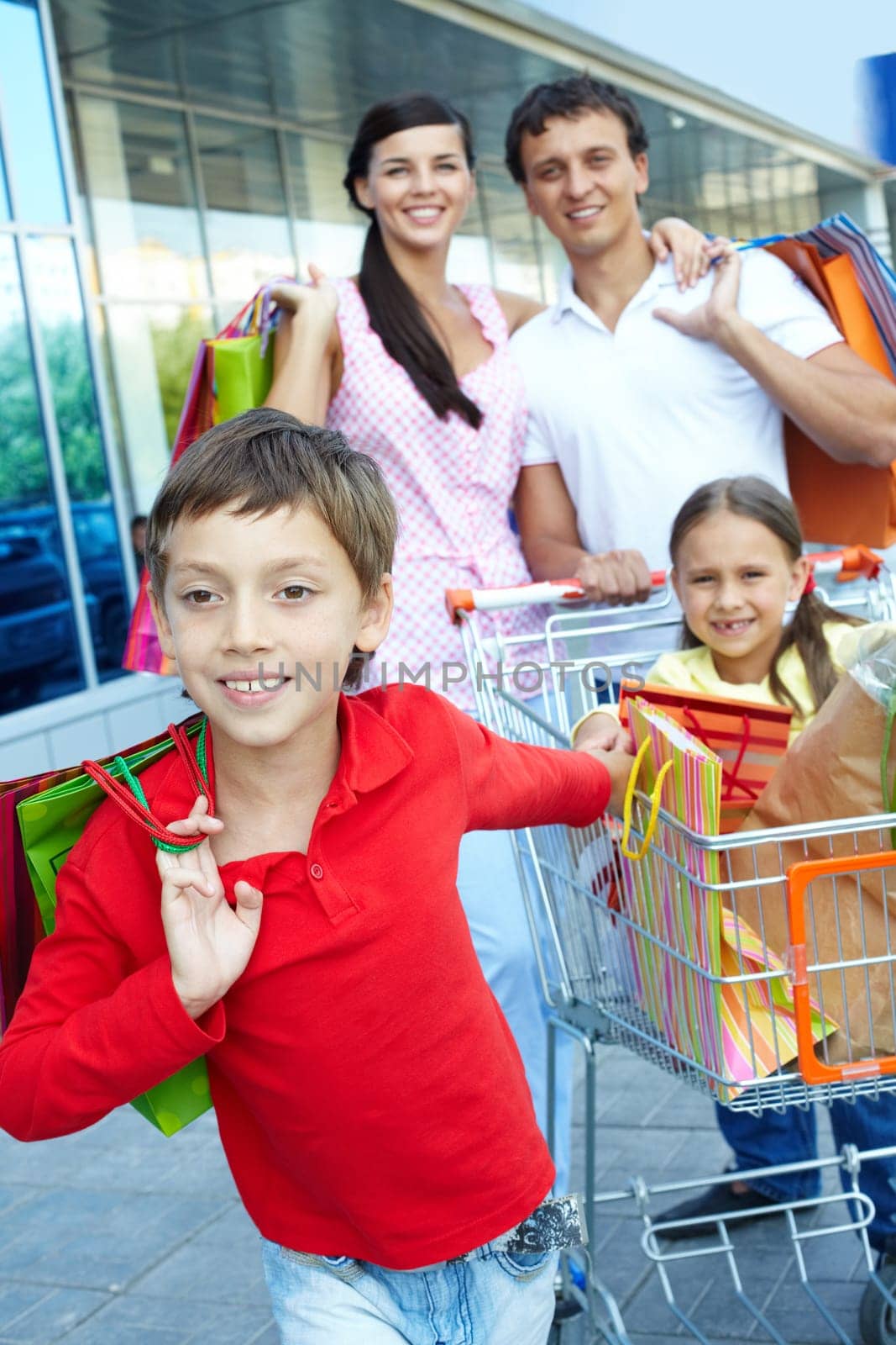 Little boy with sister and parents with shopping bags behind