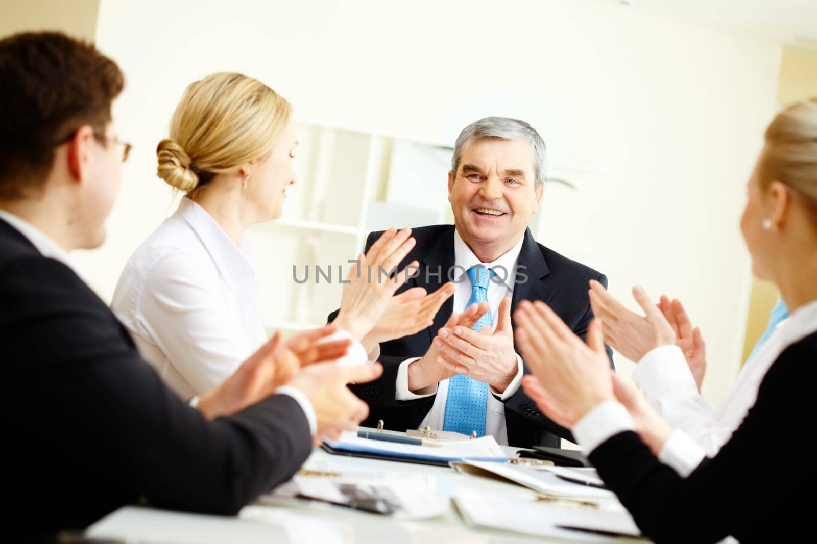Image of senior leader surrounded by his colleagues applauding to him