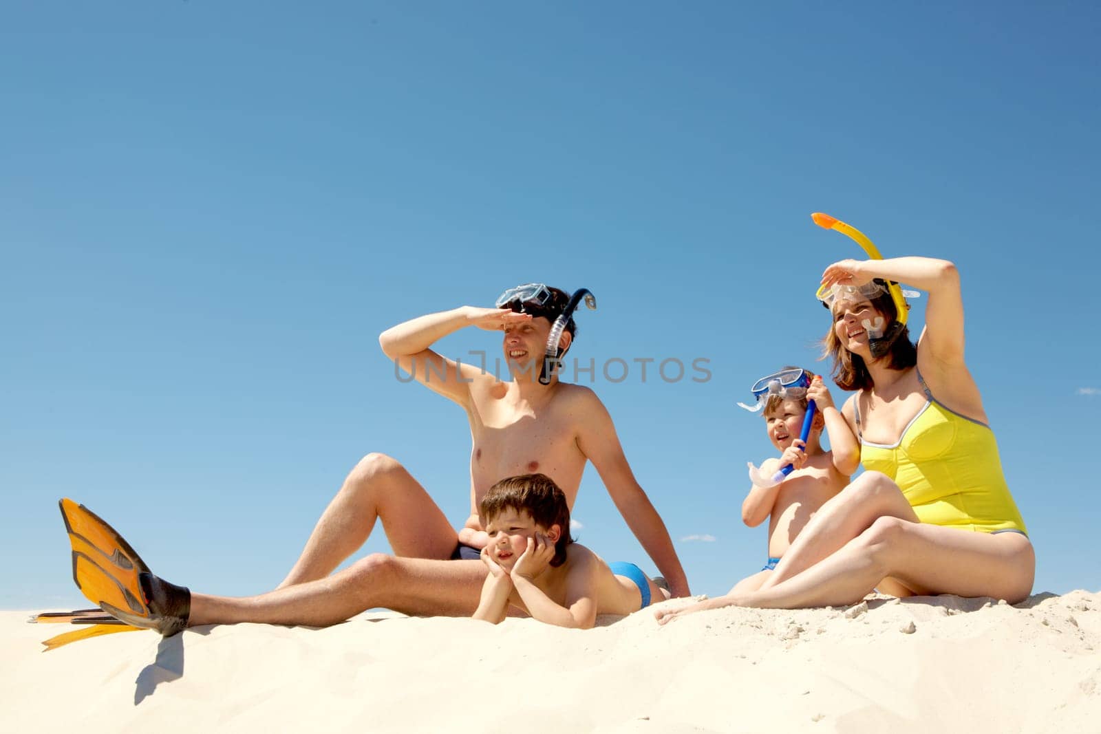 Portrait of modern family in scuba equipment looking forwards against blue sky