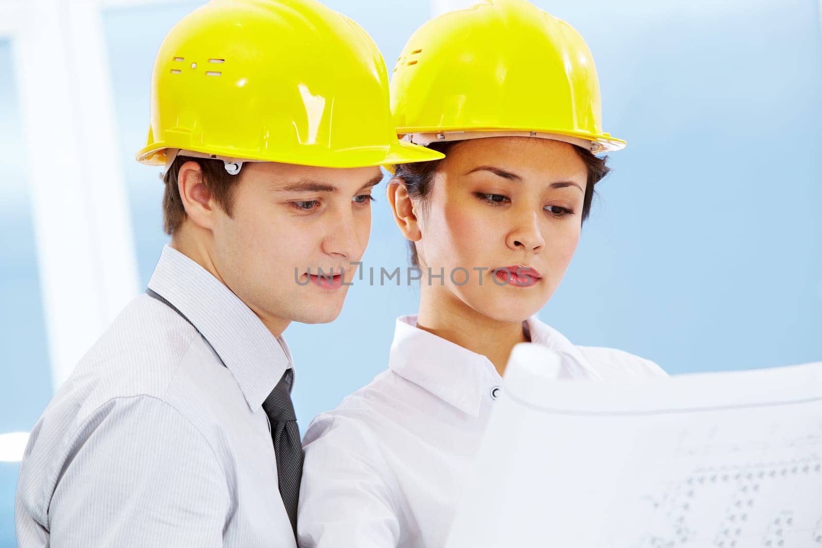 Portrait of two architects in helmets looking document at meeting