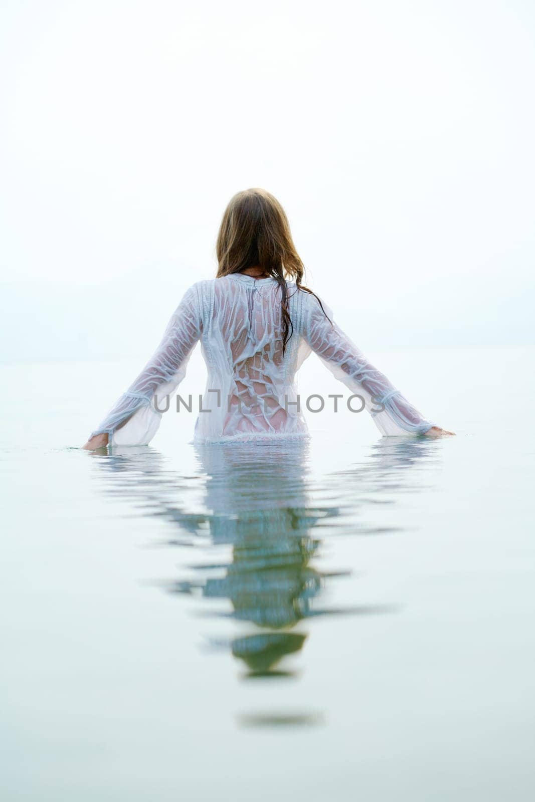 Rear view of beautiful female bathing in blue water