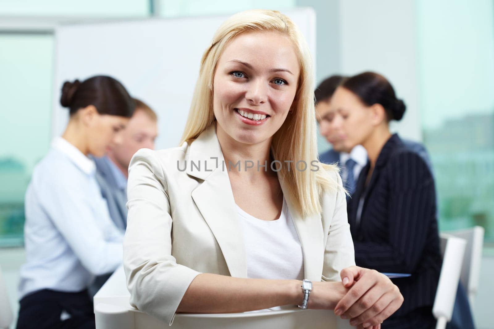 Portrait of business leader looking at camera and smiling with her colleagues in the background
