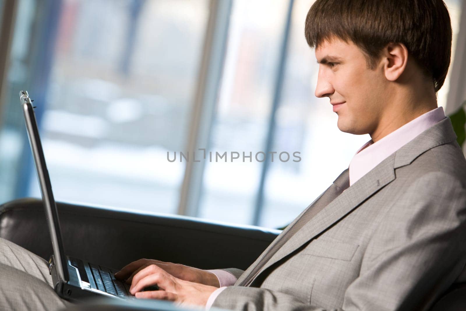 Photo of successful manager typing on laptop and looking at its screen