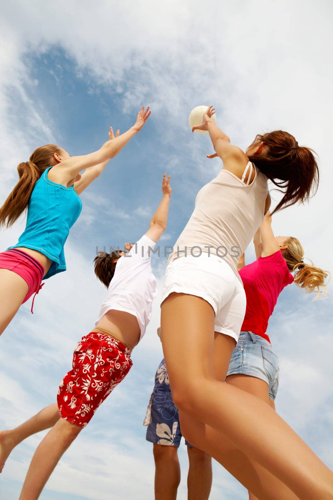 Photo of teenage friends playing with ball on background of cloudy sky