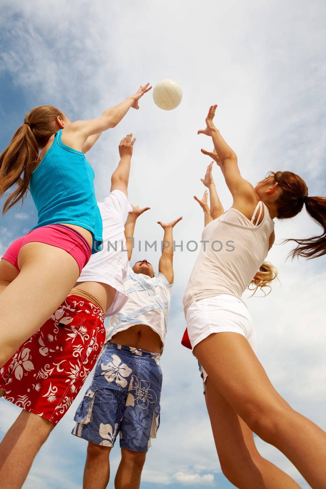 Photo of teenage friends playing with ball on background of cloudy sky