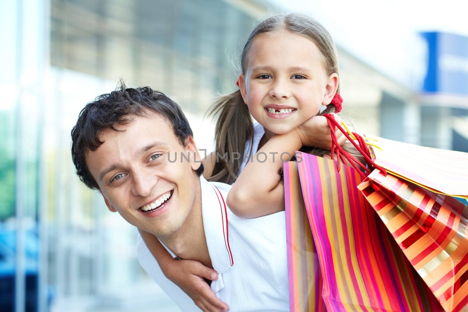 Portrait of father with daughter and shopping bags on back