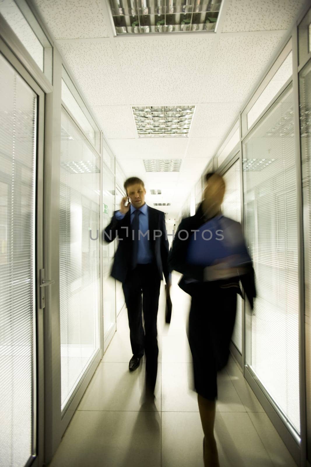 Portrait of business people walking down long corridor in office building