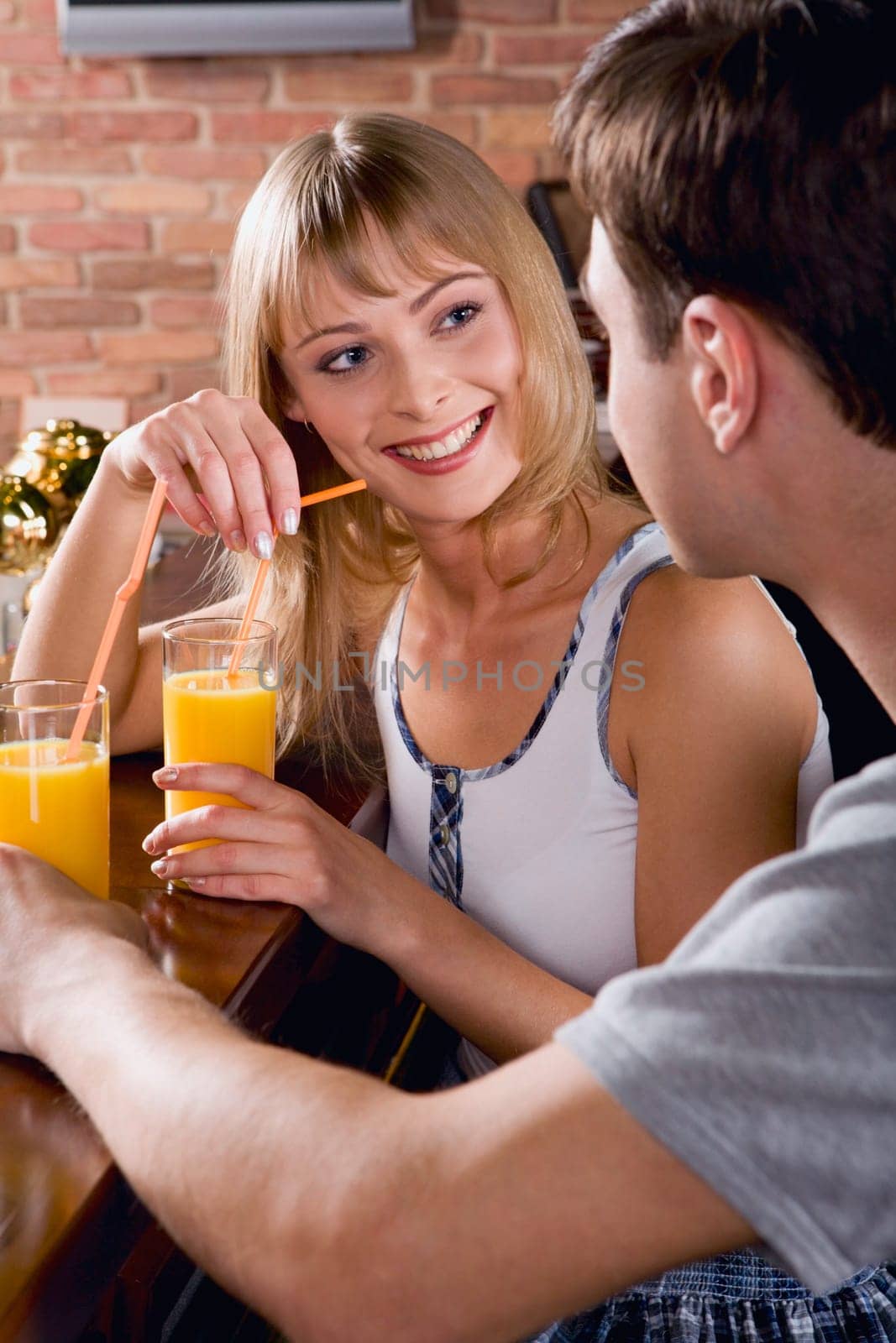 Smiling pretty woman is looking at her boyfriend in the bar