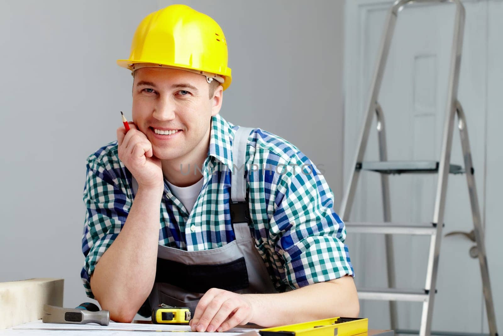 Portrait of a cheerful repairman in helmet sitting at table