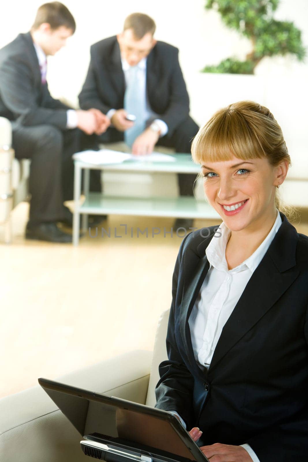 Portrait of business woman sitting on the sofa and holding laptop in the office building