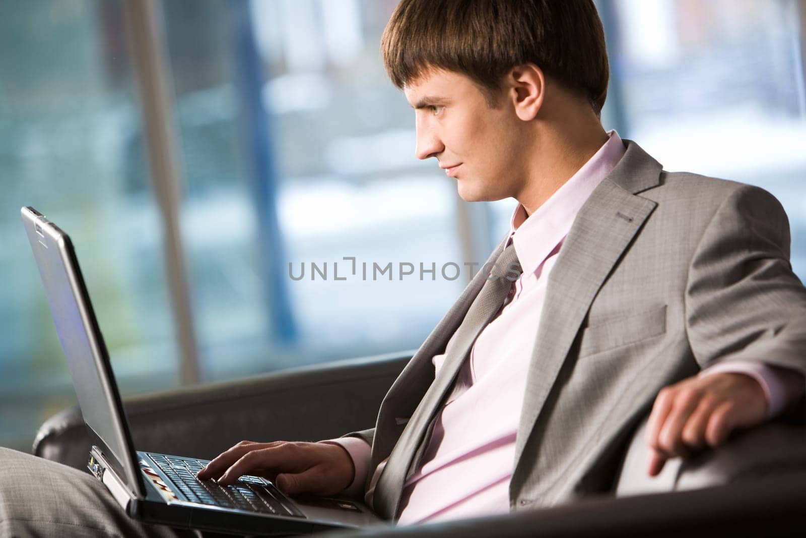 Photo of smart businessman working on laptop in office