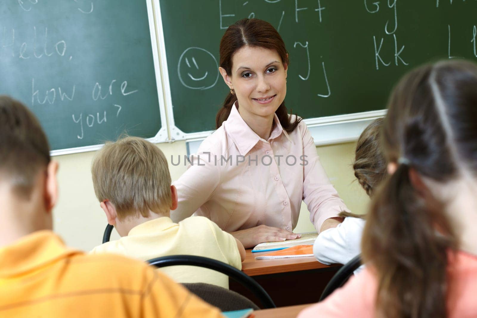 Portrait of smart teacher at workplace looking at schoolkids in classroom