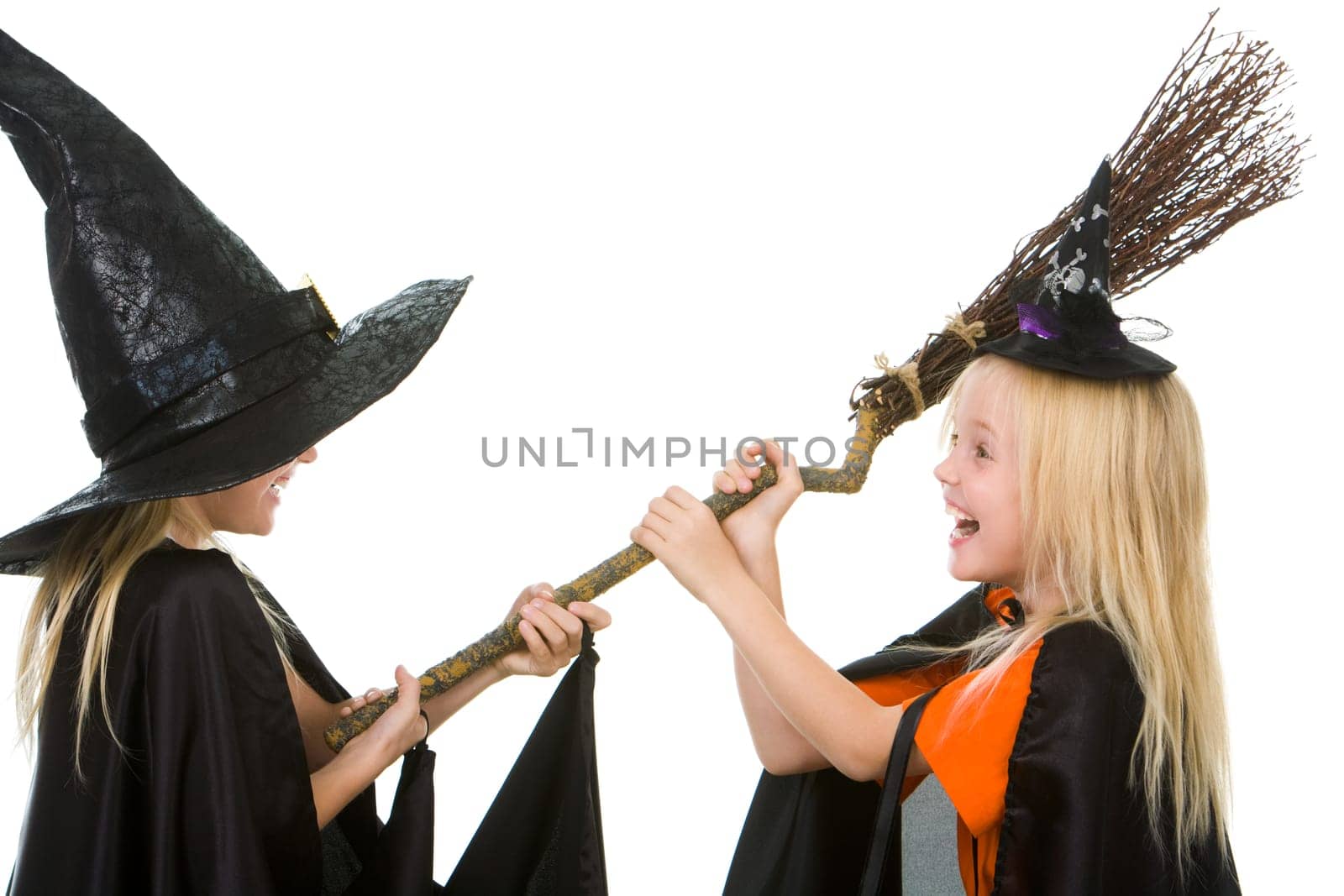 Portrait of girl twins in black hats and black clothing sharing broom