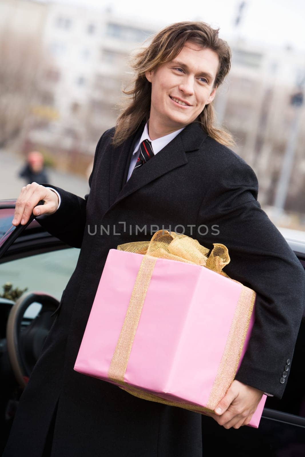 Portrait of attractive young entrepreneur with present in hand somewhere outside