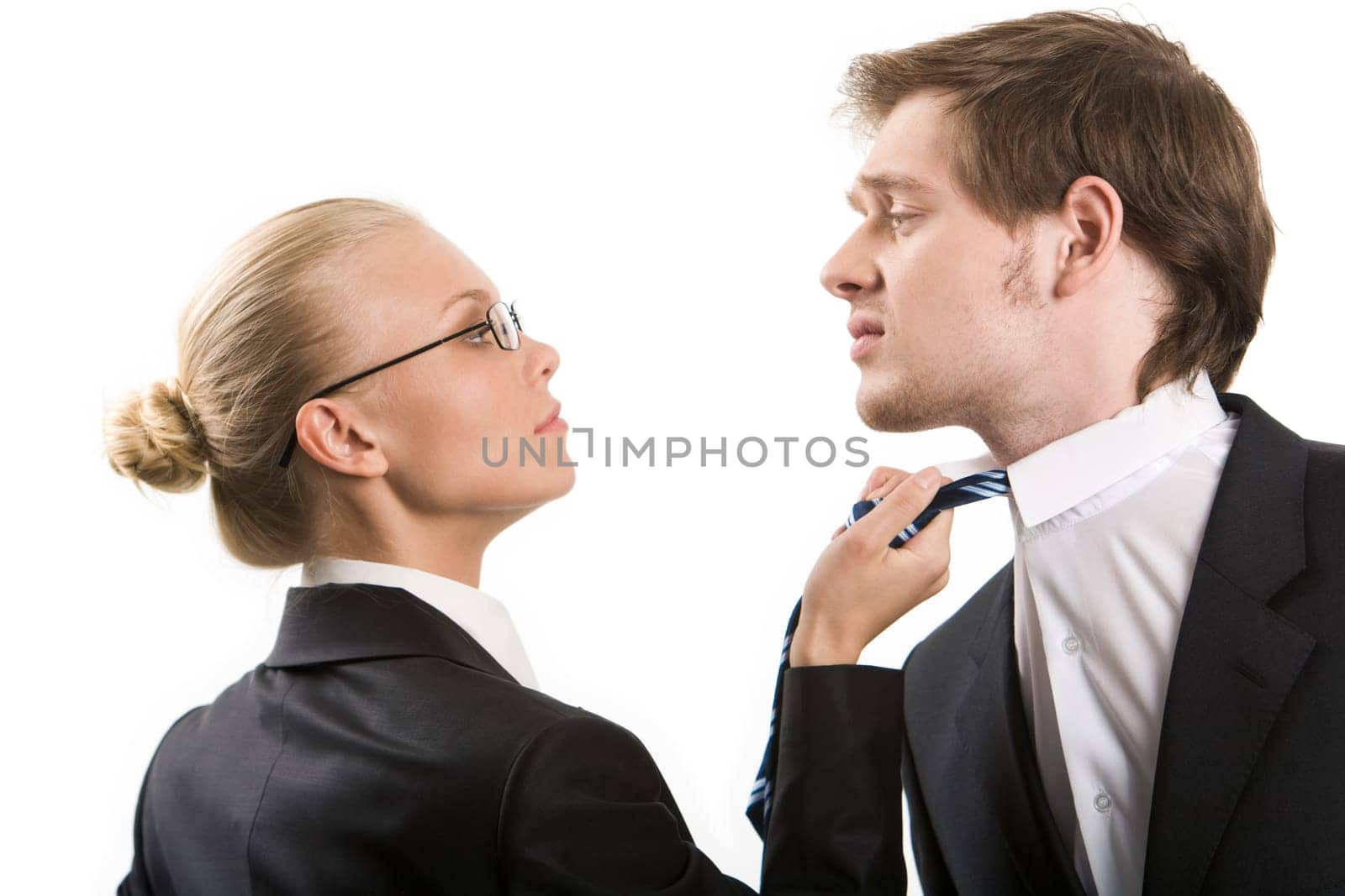 Image of business woman holding by mans tie and both looking at each other