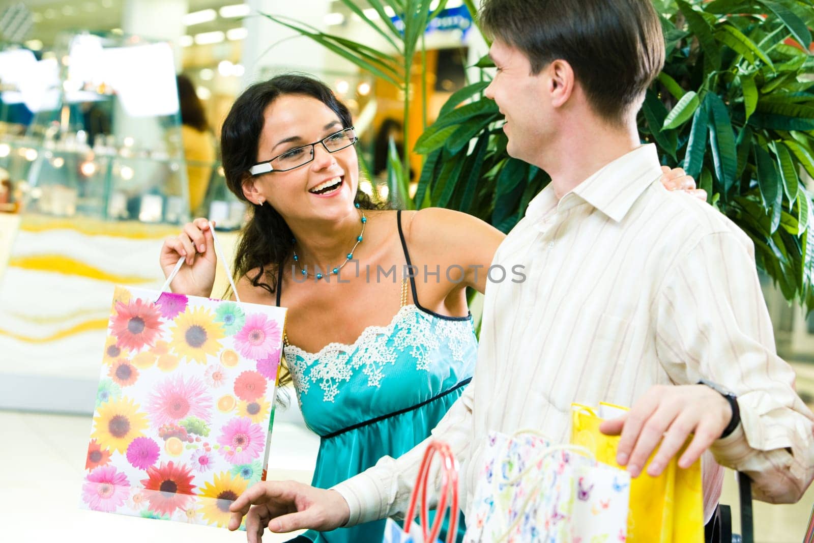 Image of beautiful girl looking happily at young man and laughing in the store