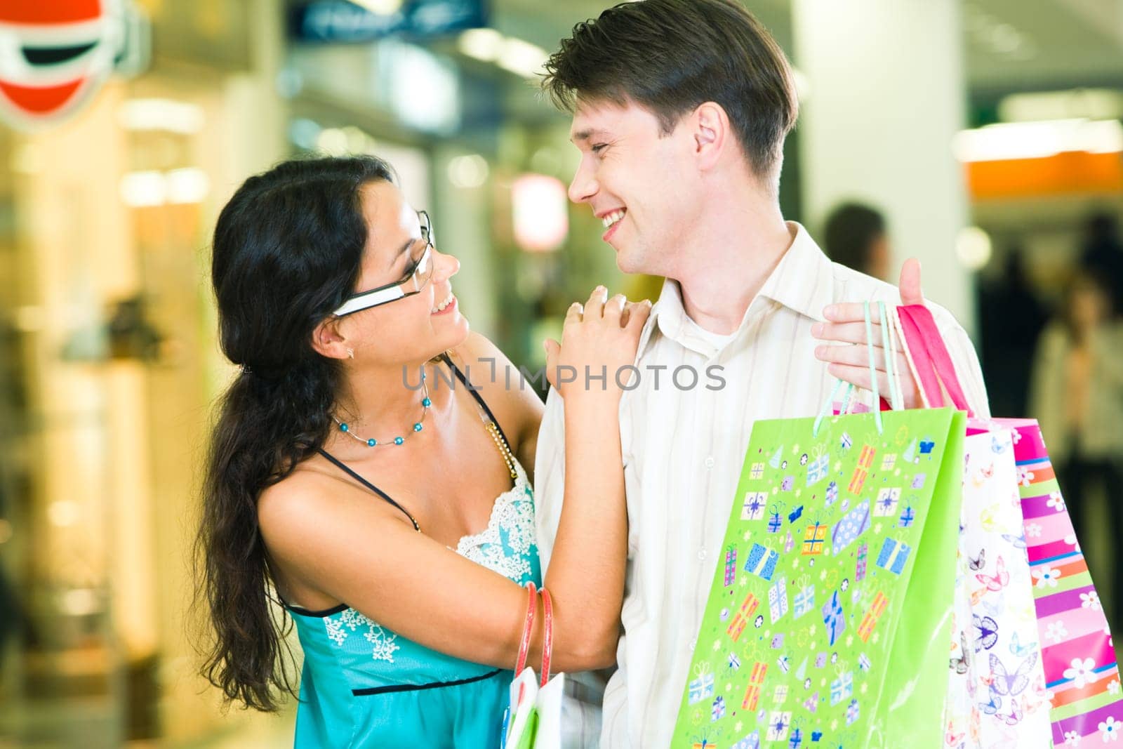 Portrait of a young couple carrying bags and looking at each other with smiles