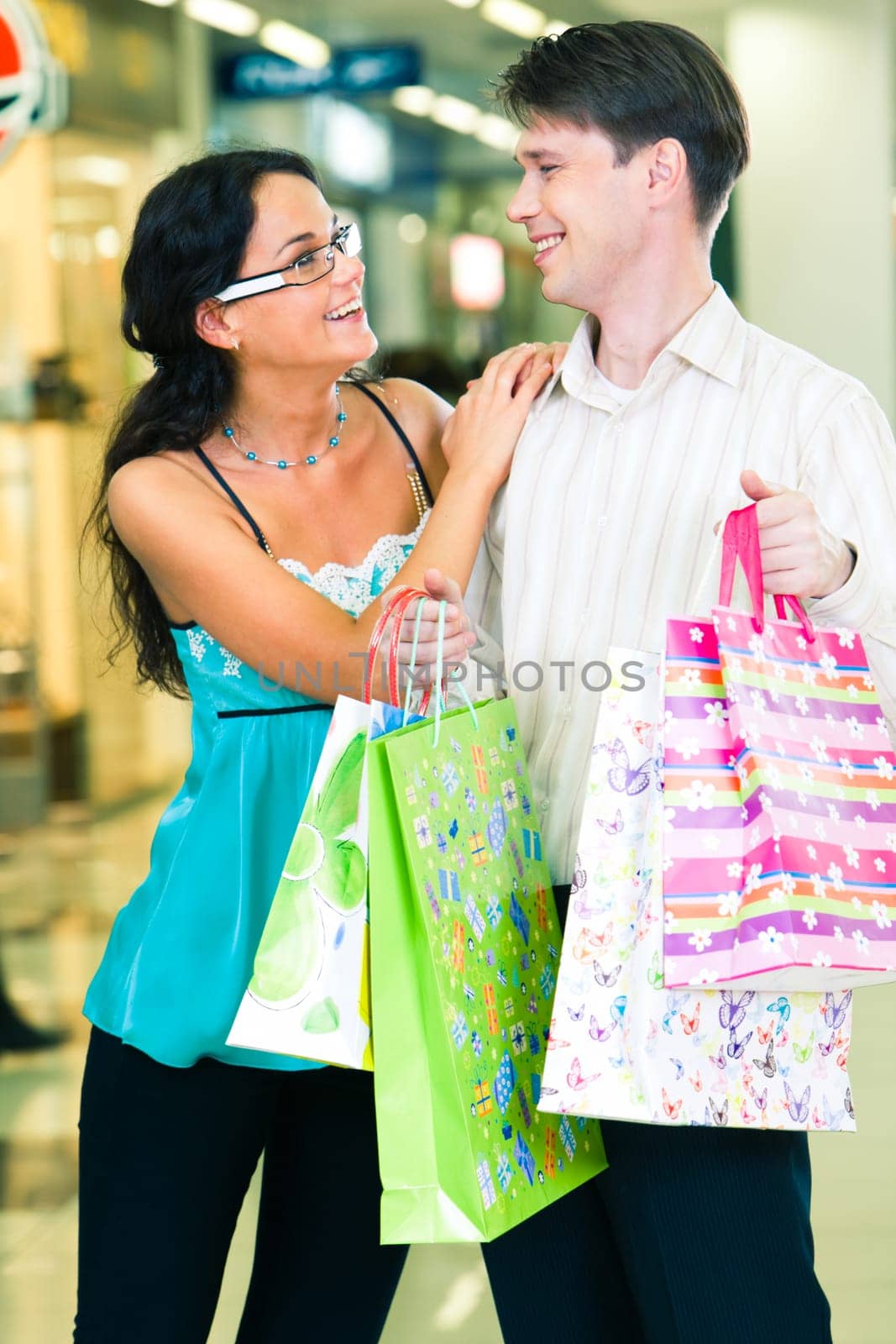 Photo of young man and woman standing in the trade centre and looking at each other happily