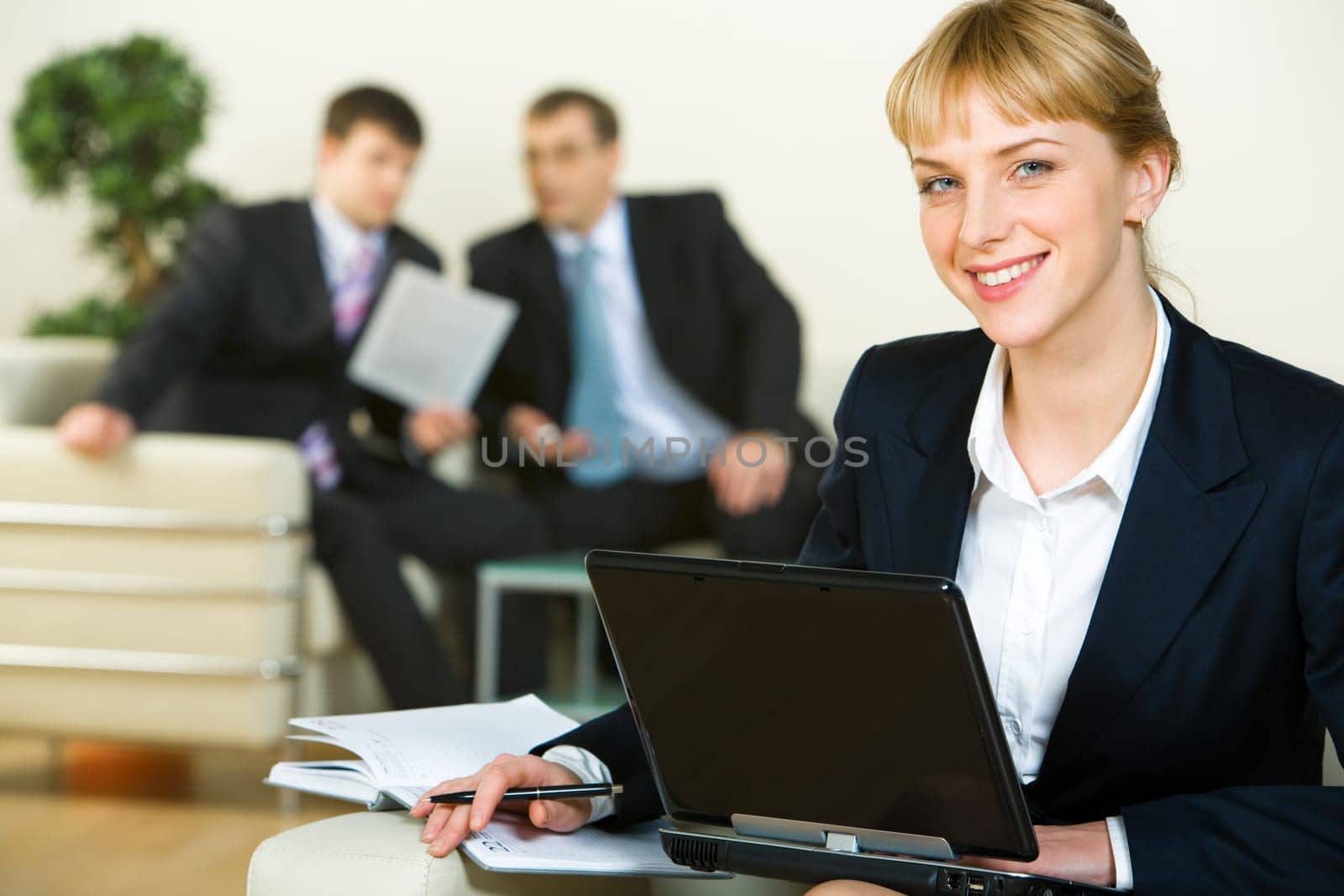 Portrait of confident woman looking at camera during her work on the background of business men
