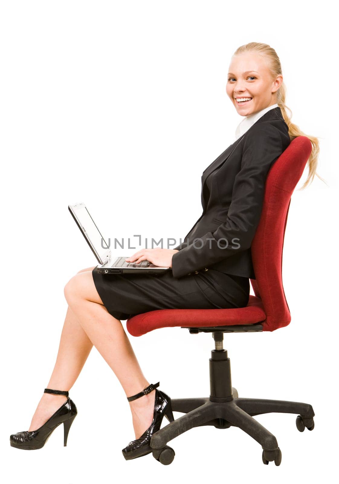 Profile of serious businesswoman sitting on arm-chair and smiling at camera while typing