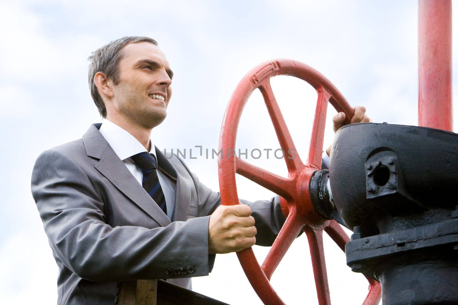 Portrait of strong leader holding rudder and looking forwards with smile