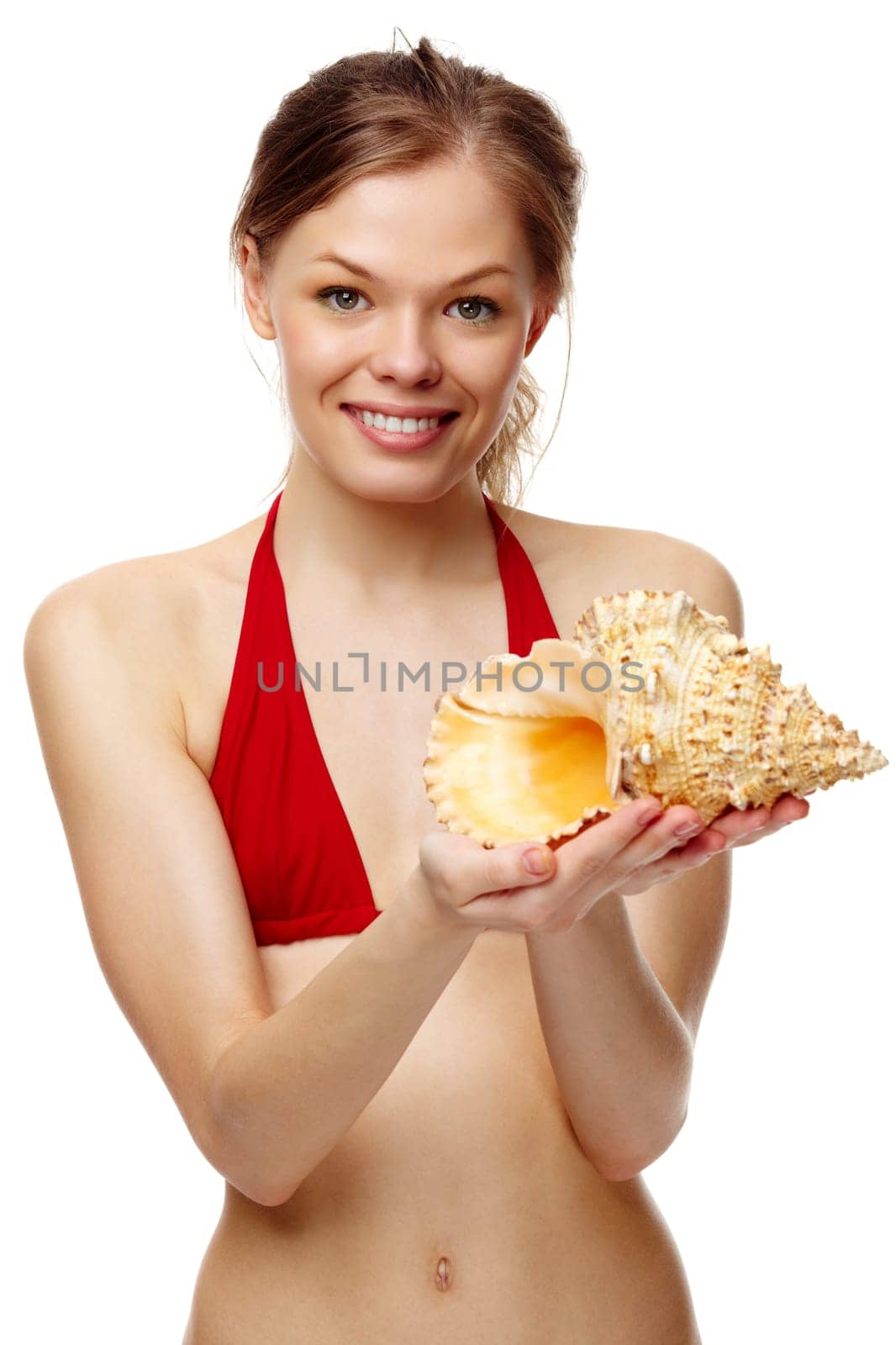 Portrait of a young girl in bikini with seashell looking at camera
