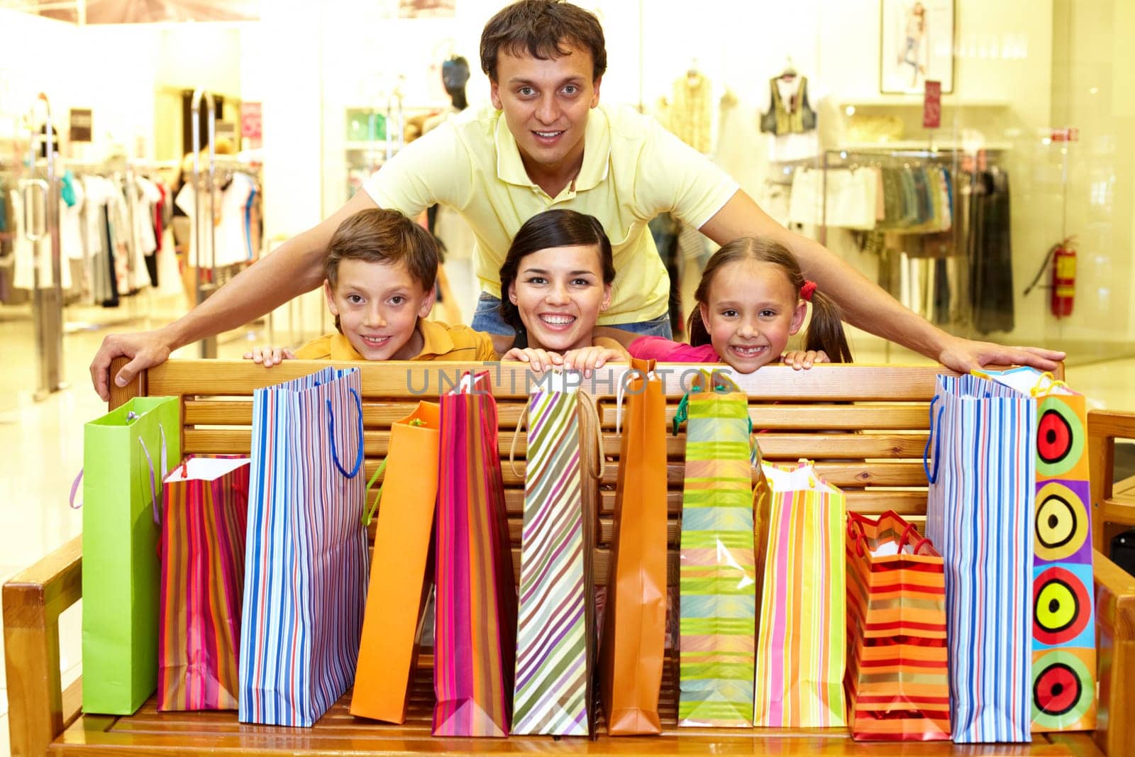 Portrait of a family at bench with plenty of shopping bags looking at camera and smiling