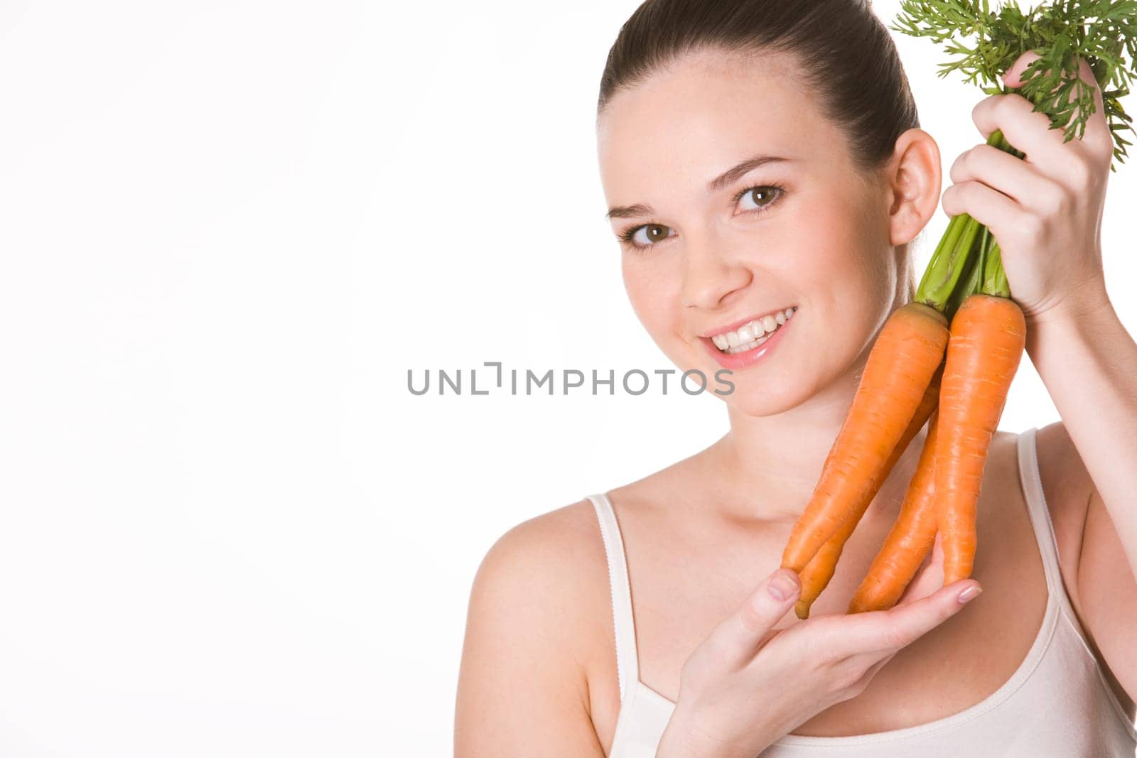 Portrait of pretty girl with ripe carrots smiling at camera over white background