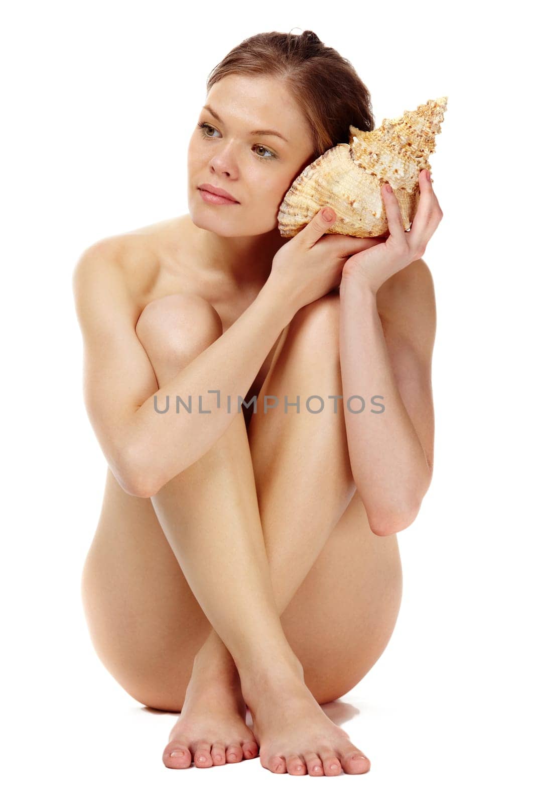 Portrait of a naked girl listening to the seashell