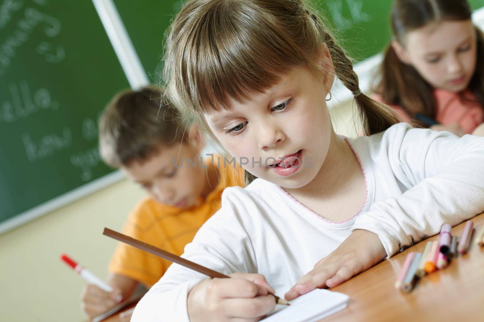 Portrait of smart schoolgirl drawing at lesson in classroom