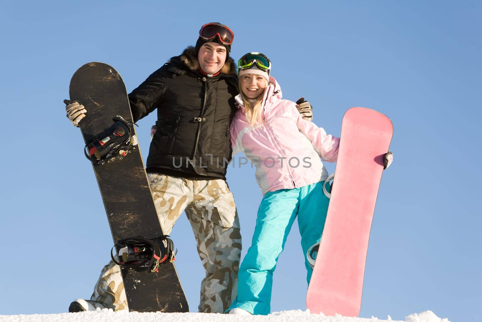 Portrait of joyful man and woman standing on snow with boards in hands
