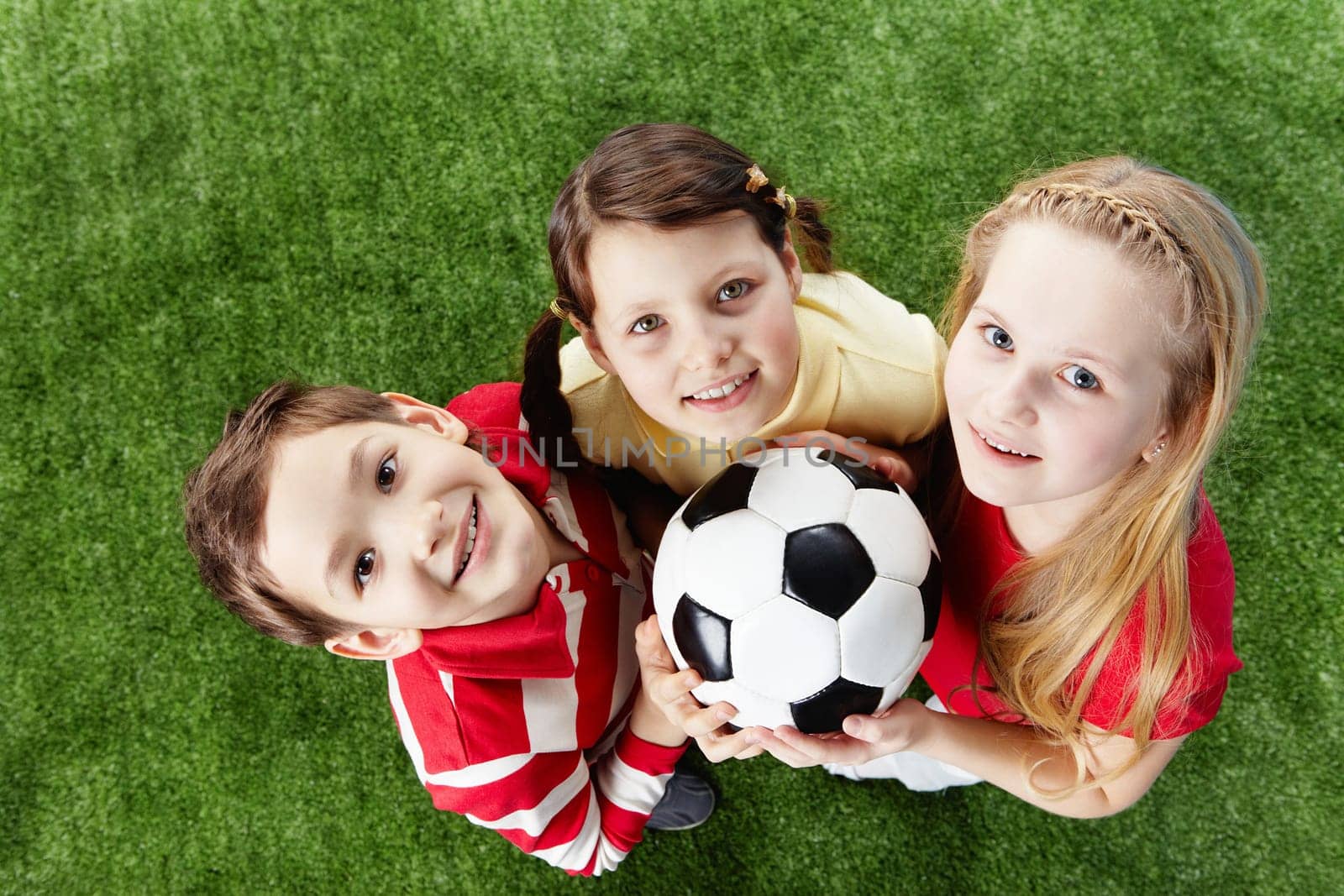 Image of happy friends on the grass with ball looking at camera