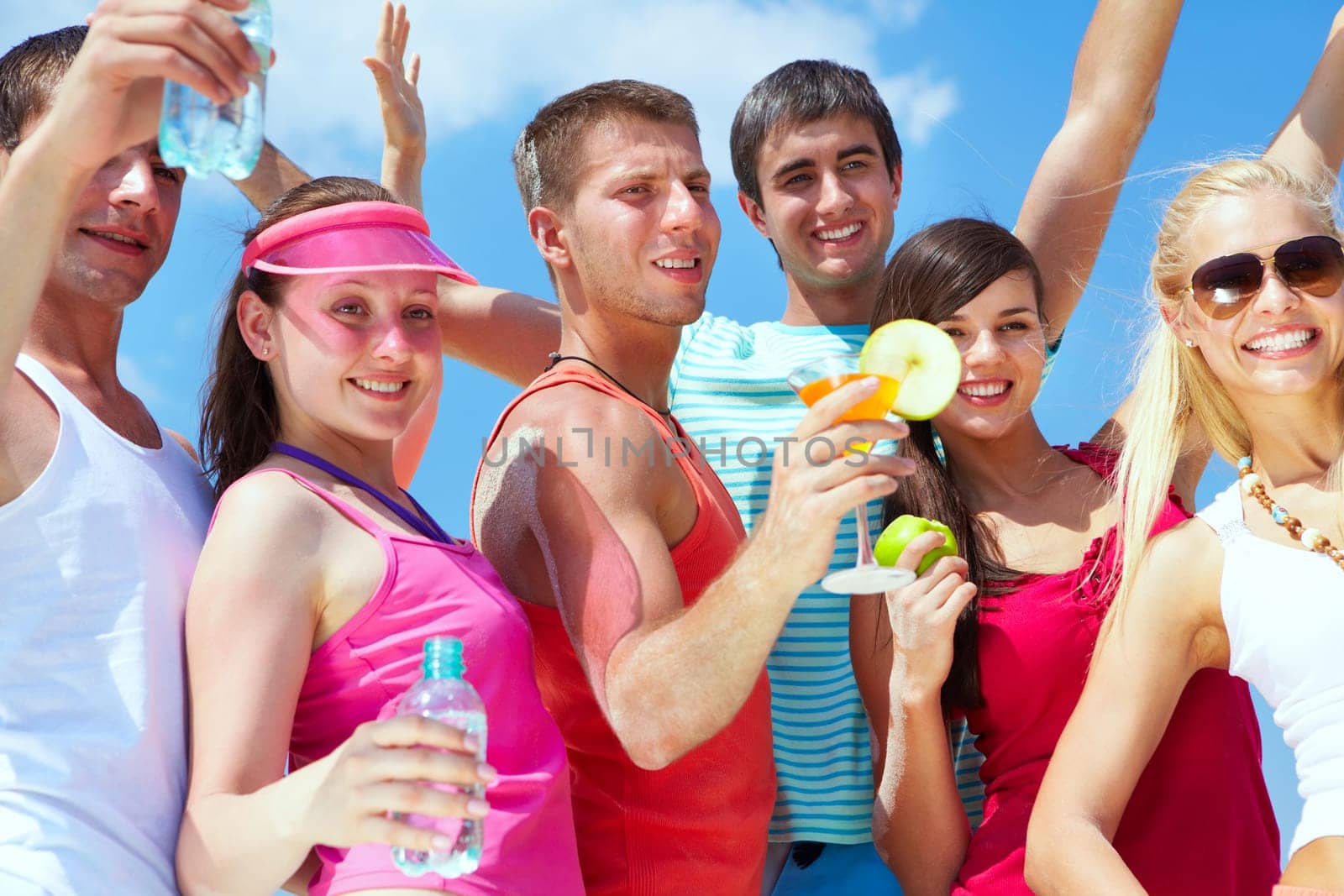 Portrait of happy young friends holding cocktails during beach party