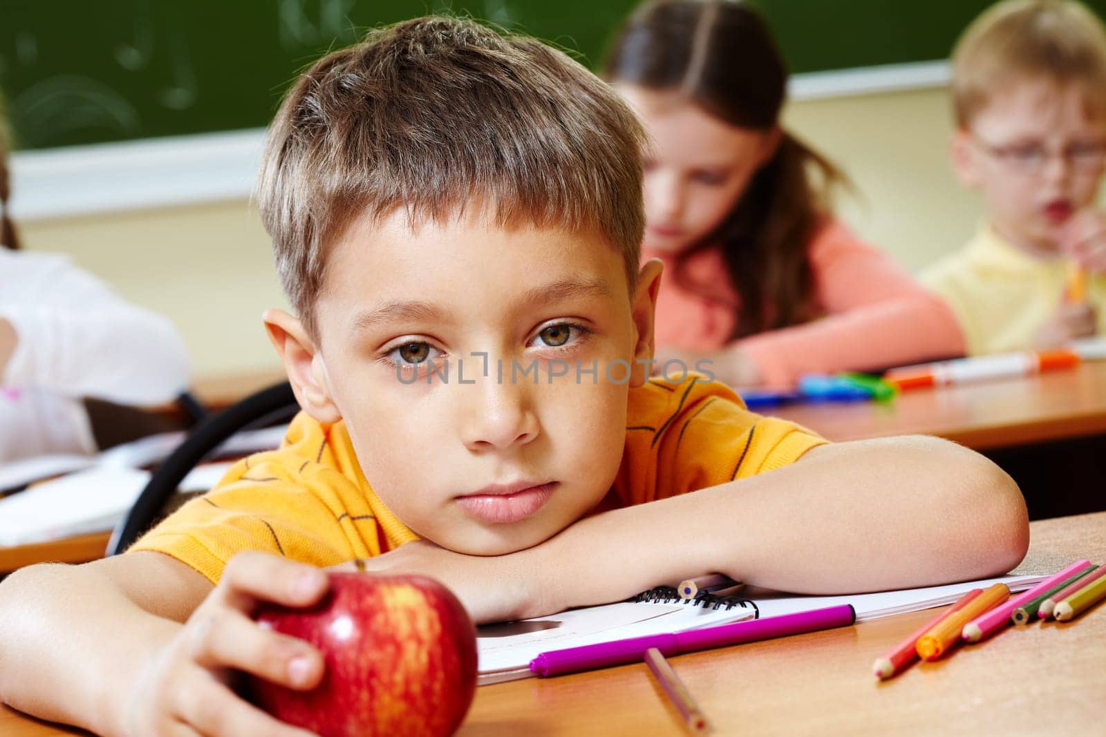 Close-up of schoolboy putting his head on arm and looking at camera