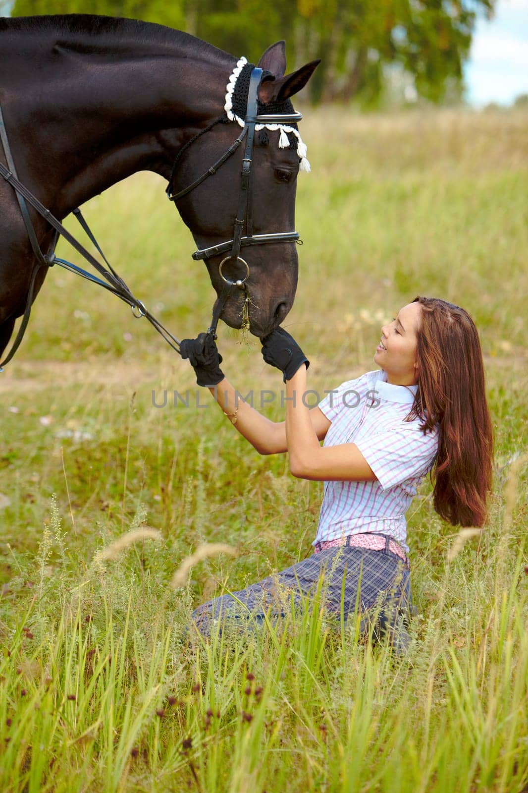 Portrait of smiling female feeding purebred horse with grass outdoors