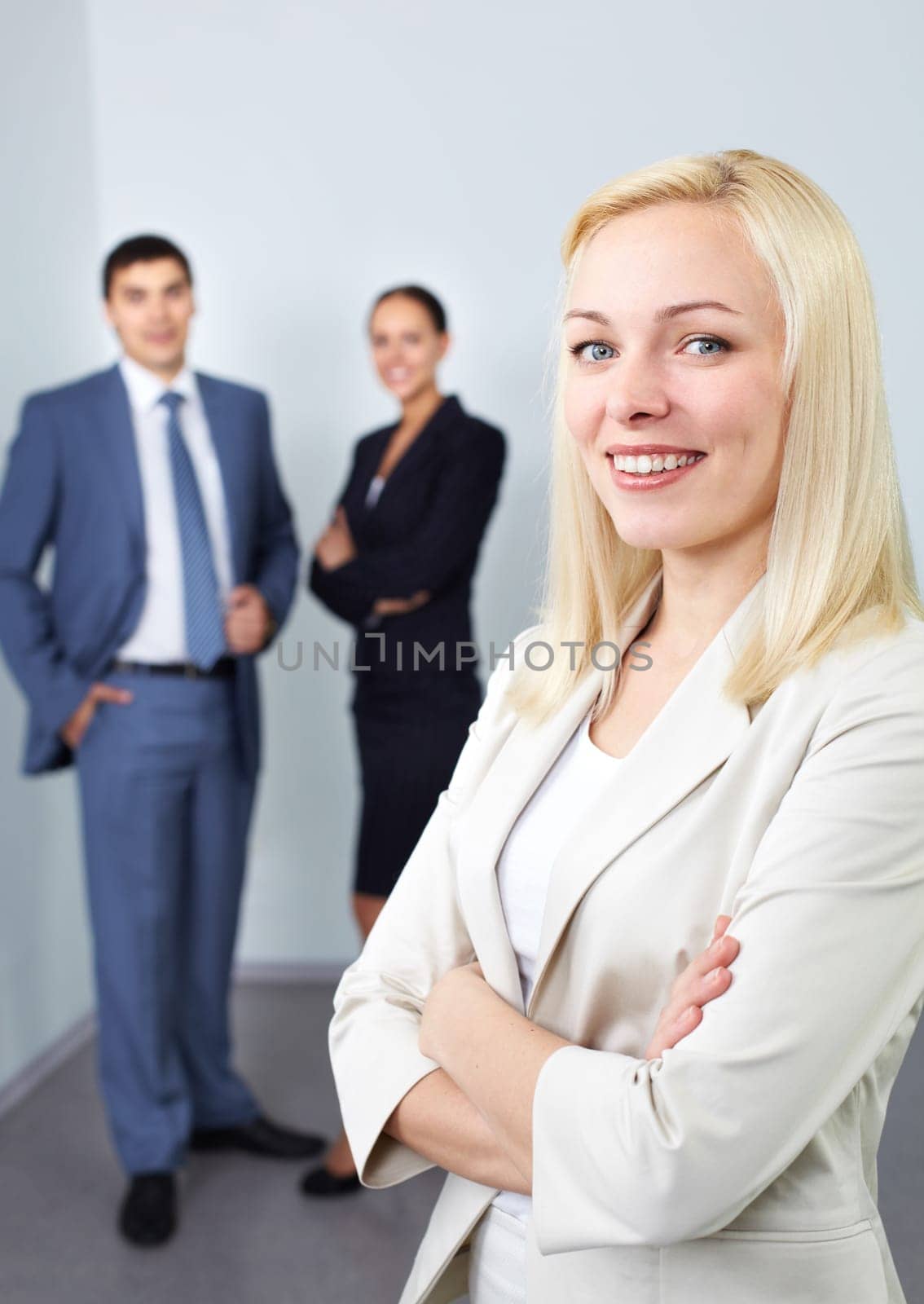 Portrait of young businesswoman with two colleagues in the background