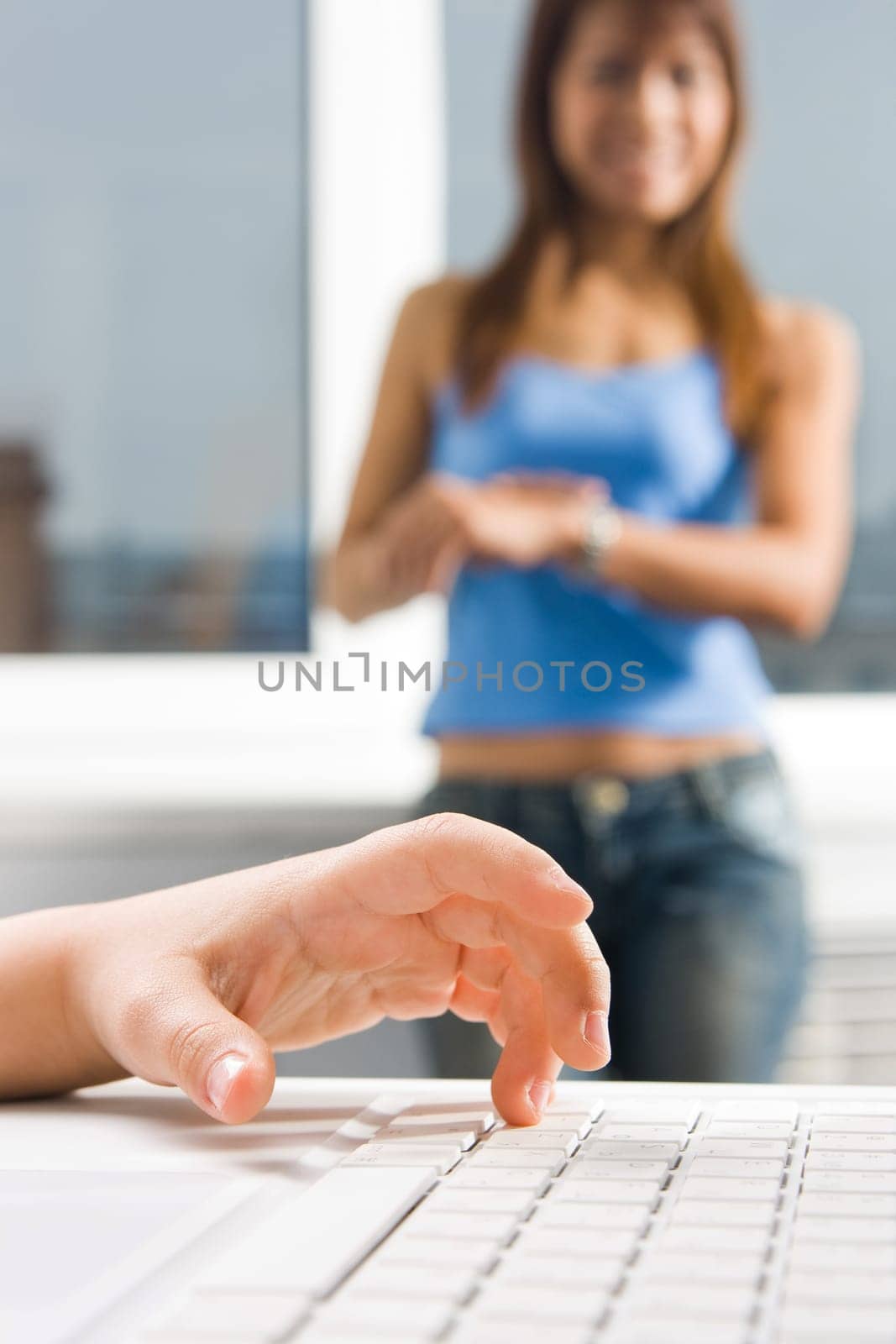 Close-up of childs palm over laptop keyboard button with woman standing at background