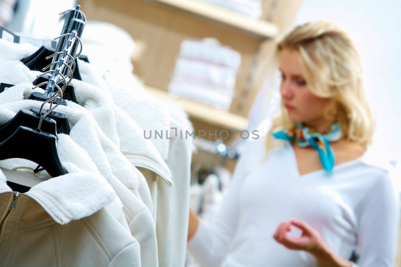 Close-up of woman choosing clothes with jackets in front