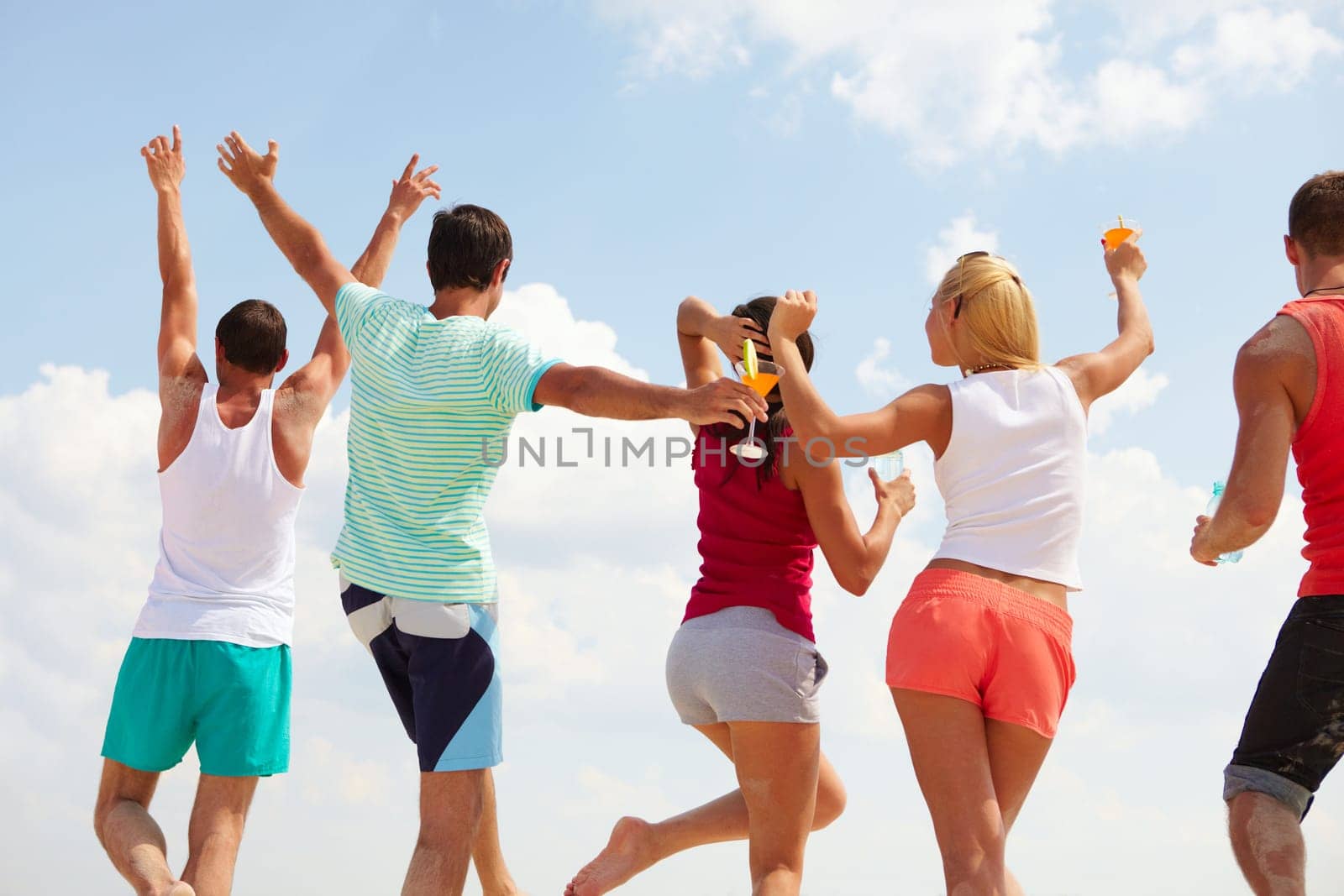 Backs of happy young friends dancing at beach party
