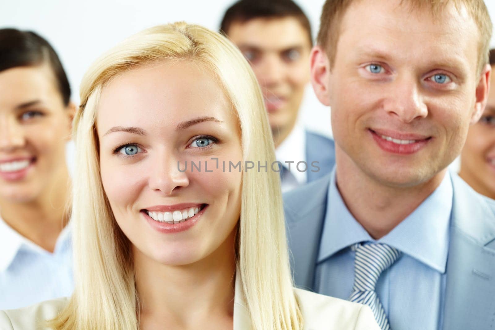 Portrait of cheerful female looking at camera with several employees behind