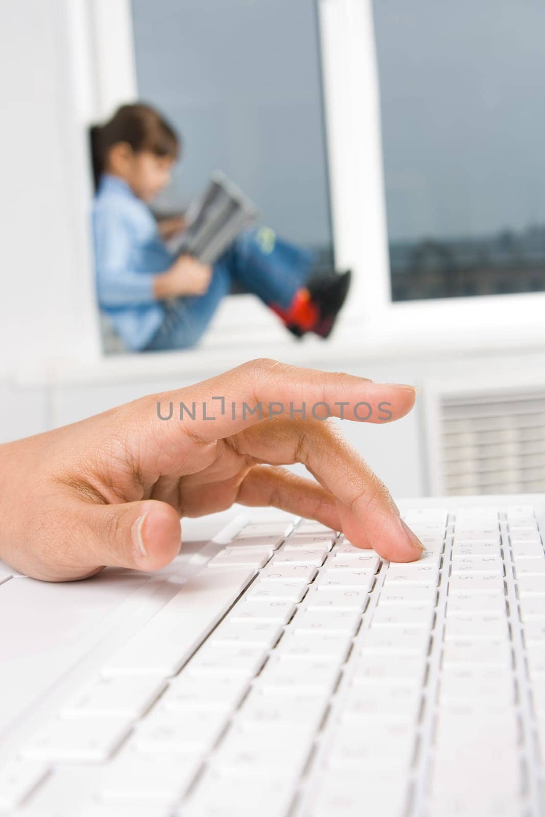 Close-up of females hand over keyboard button with a child at background