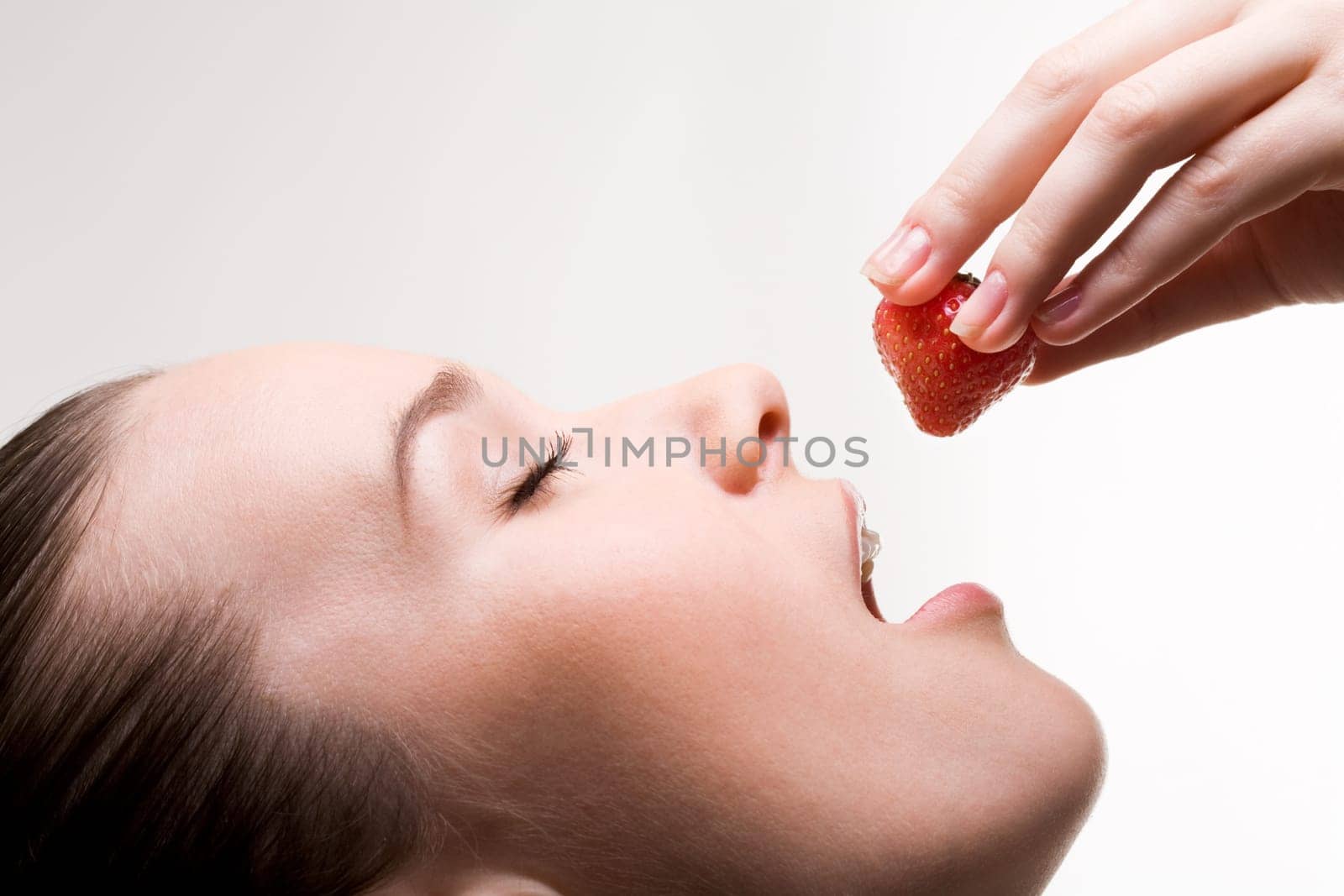 Image of pretty girl with open mouth and ripe strawberry in hand