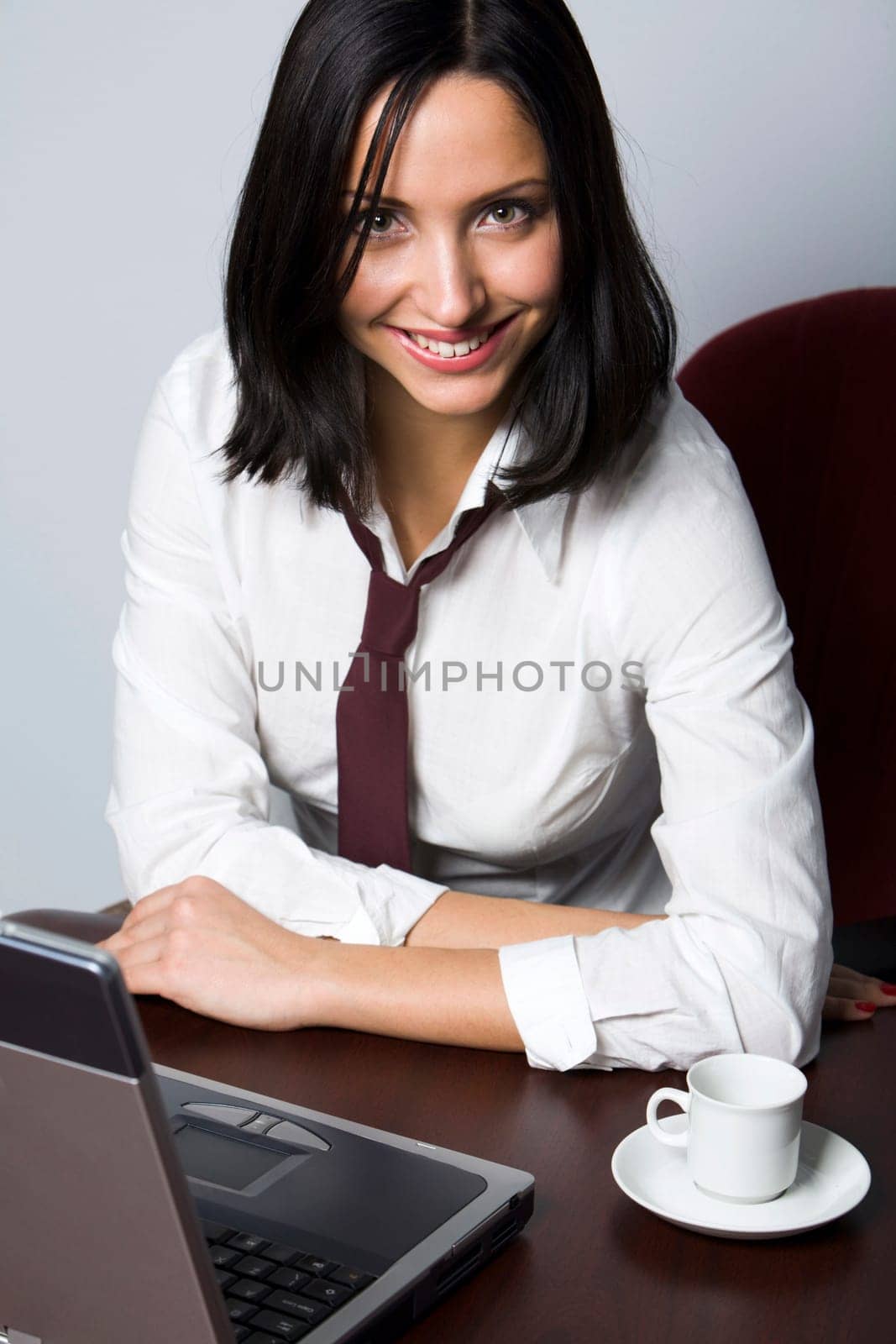 Smiling Hispanic brunette drinking coffee in front of her lap top